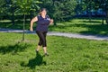 Woman with obesity jogging in public park on a sunny summer day.