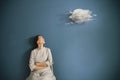 Woman observes astonished surreal cloud flying in her room, abstract concept