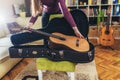 Woman observes and putting a classic brown guitar from a black case