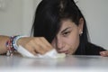 Woman with obsessive compulsive disorder cleaning table with detergents. OCD concept