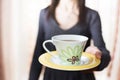 Woman offering a cup of tea blurring