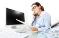 Woman at office desk with computer documents and phone