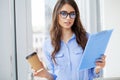 A woman in the office near the window, holding documents in her hands Royalty Free Stock Photo