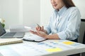 Woman office worker sitting to working and pressing a calculator to calculate the profit of a new business project