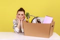 Woman office worker sitting at workplace with cardboard box with her things, dismissal, bankruptcy. Royalty Free Stock Photo