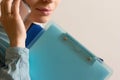 woman-office worker talking on the phone with lots of folders on hand