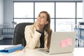 Woman at office working at laptop computer desk smiling happy thoughtful and pensive Royalty Free Stock Photo