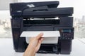 Woman officer pull printed business documents from multi functional printer