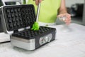 Woman is oiling the waffle iron in her modern kitchen