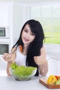 Woman with OK sign eats salad in kitchen Royalty Free Stock Photo