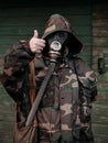 Woman with old gas mask and army jacket with a hood show thumb up. Concept - Nuclear Disarmament and Radiation Protection,