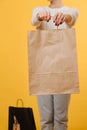 Woman in old pale jeans holding shopping paper bag with hands outstretched