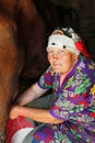 Woman old poor farmer milking cow Royalty Free Stock Photo