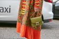Woman with olive green Furla bag and orange and yellow floral design jacket before Antonio Marras fashion