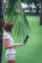 Woman online shopping concept. Freelancer woman in the green park with modern laptop. Bali island. Royalty Free Stock Photo