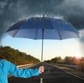 Woman with open blue umbrella on empty asphalt road, closeup