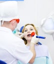 Woman with open mouth receiving dental filling dry