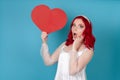 woman with open mouth in white dress and red hair holding a big red paper heart and holding her face Royalty Free Stock Photo