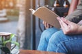 A woman opening a book to read with notebooks and coffee cup on wooden table in cafe Royalty Free Stock Photo