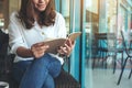 A woman opening a book to read with notebooks and coffee cup on wooden table in cafe Royalty Free Stock Photo