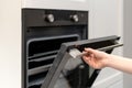 Woman opening built-in oven in white kitchen cabinet Royalty Free Stock Photo