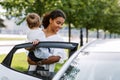 Woman opening a car door and putting her little daughter into it