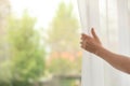 Woman opening curtain indoors, closeup. Space for text