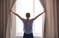 Woman opening curtains and looking out of window Royalty Free Stock Photo