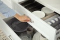 Woman opening drawer of kitchen cabinet with different dishware and towels, closeup Royalty Free Stock Photo
