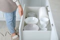 Woman opening drawer with plates and bowls in kitchen, closeup Royalty Free Stock Photo