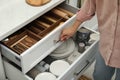 Woman opening drawers of kitchen cabinet with different dishware and utensils, closeup Royalty Free Stock Photo