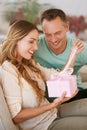 Woman opening gift, man and happy with surprise for birthday or anniversary, love and support with romance. Couple in Royalty Free Stock Photo
