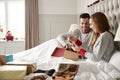 Woman Opening Gift Of Necklace In Bed At Home As Couple Exchange Presents On Christmas Day Royalty Free Stock Photo