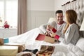 Woman Opening Gift Of Necklace In Bed At Home As Couple Exchange Presents On Christmas Day Royalty Free Stock Photo