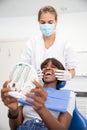 Woman opening mouth and looking at her teeth in mirror in clinic Royalty Free Stock Photo