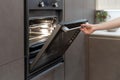 Woman opening oven with light built-in in kitchen cabinet Royalty Free Stock Photo