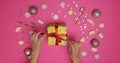 Woman opening present box on pink background. Christmas and New Year celebration concept. Overhead view. Royalty Free Stock Photo