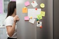 Woman opening refrigerator door with paper sheets