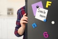 Woman opening refrigerator door with SMILE MORE note, closeup