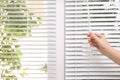 Woman opening white horizontal window blinds