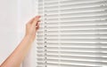 Woman opening white horizontal window blinds