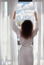 Woman opens curtains and looks up Royalty Free Stock Photo