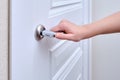 A woman opens the door holding the handle, hand close-up. White woo Royalty Free Stock Photo