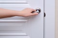 A woman opens the door holding the handle, hand close-up. White woo Royalty Free Stock Photo