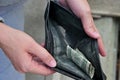 Woman opens an old wallet containing only dust and dirt and one crumpled dollar