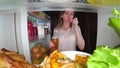 Woman opens the refrigerator at night. night hunger. diet gluttony