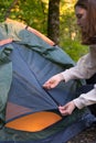 A woman opens the tent door in the woods. Camp in nature. Hiking, tourist in the mountains Royalty Free Stock Photo