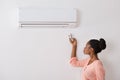 Woman Operating Air Conditioner With Remote Control Royalty Free Stock Photo