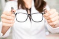 Woman optician holding black frame eyeglasses in hand