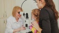 Woman optometrist checks eyesight at little girl - child`s ophthalmology Royalty Free Stock Photo